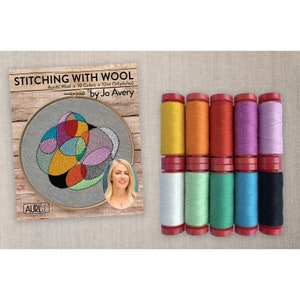 May include: An embroidery kit with a completed design in a wooden hoop, featuring colorful abstract shapes. The kit includes ten spools of Aurifil wool thread in various colors, including yellow, orange, red, purple, and blue. The text on the kit reads "STITCHING WITH WOOL by Jo Avery."