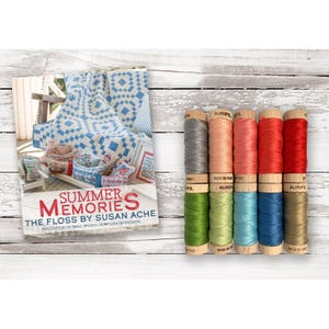 May include: A set of ten small spools of Aurifil cotton embroidery floss in various colors, including gray, peach, coral, red, green, light green, blue, and tan, alongside a promotional card titled Summer Memories The Floss By Susan Ache.