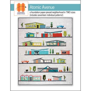 May include: A quilt featuring a colorful, mid-century modern neighborhood design. The quilt showcases various houses, cars, and trees in a repeating pattern. The text "Atomic Avenue" and "Hunter's Design Studio" are visible.