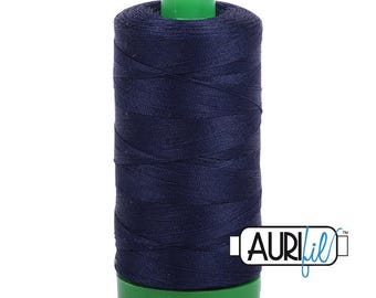 Op de afbeelding: Een klos donker marineblauw naaigaren gewikkeld rond een cilindrische kern met een felgroene plastic boven- en onderkant. De merknaam AURIfil staat in zwarte en blauwe letters gedrukt op een wit rechthoekig label aan de zijkant.