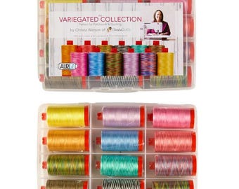 May include: A clear plastic storage case containing twelve spools of variegated sewing thread in various colors. The label reads VARIEGATED COLLECTION by Christa Watson of ChristaQuilts. The spools are arranged in a grid with red plastic caps.