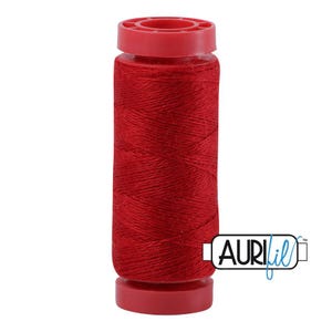 May include: A spool of vibrant red sewing thread wound onto a cylindrical plastic core with matching red end caps. The spool features a prominent logo with the text AURIfil in a stylized black and blue font, positioned at the bottom right.