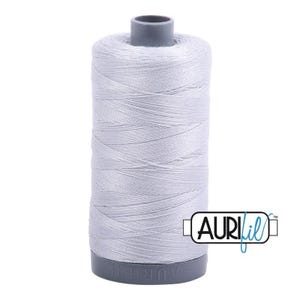 May include: A cylindrical spool of light gray sewing thread with a smooth, consistent texture. The spool features a dark gray plastic base and top cap, with the brand name AURIfil printed in a black and blue logo on the lower right side.