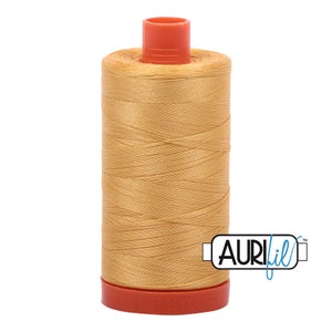 May include: A spool of Aurifil thread in a golden yellow color. The spool is labeled "Aurifil" in blue lettering.