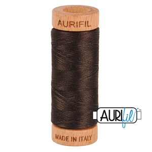 May include: A spool of brown Aurifil thread with a wooden bobbin. The bobbin is labeled "Aurifil" and "Made in Italy".
