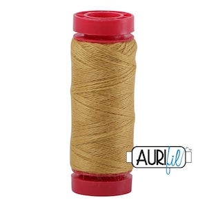 May include: A spool of golden-brown sewing thread wound around a cylindrical core with bright red plastic caps at the top and bottom. The brand name AuriFil is printed in black and blue text on a white rectangular label attached to the side.