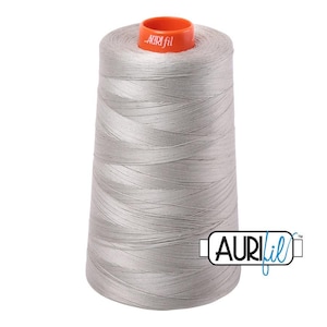 May include: A large spool of light gray sewing thread with a conical shape. The top of the spool features a bright orange plastic cap with the white text Aurifil printed on it. The brand logo Aurifil is also visible in the bottom right corner.