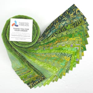 May include: A jelly roll of green fabric strips featuring various batik patterns in shades of lime, emerald, and forest green. A white square card is attached to the top, displaying the Twisted Threads logo and contact information.