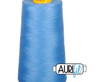 Può includere: Un grande cono di filo da cucito azzurro con un tappo superiore in plastica gialla. Il marchio AuriFil è stampato sul tappo giallo e appare anche in un logo nero e blu in basso a destra, con il testo AuriFil.