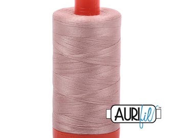 Op de afbeelding: Een klos naaigaren in de kleur oudroze met een feloranje kunststof boven- en onderkant. De klos is voorzien van de merknaam Aurifil, gedrukt in zwarte en blauwe letters op een wit rechthoekig label aan de rechteronderkant.