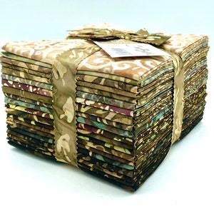 May include: A stack of fabric squares in shades of brown, green, and cream, tied with a matching ribbon. The fabric has a batik-style pattern. A small tag is attached to the ribbon. Ideal for quilting and crafting projects.