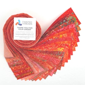 May include: A jelly roll of fabric strips in shades of red, orange, and pink with various floral and abstract patterns. A square white card is attached, featuring the text TWISTED THREADS THANK YOU FOR YOUR ORDER and contact information.