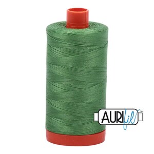 May include: A cylindrical spool of sage green sewing thread featuring a bright red plastic top and base. The spool is wrapped in smooth, tightly wound thread and includes a white rectangular logo with the black and blue text AURIfil.