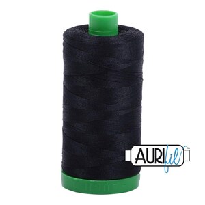 May include: A spool of black sewing thread featuring a bright green plastic top and base. The spool is cylindrical in shape with the thread wound tightly around the center. The brand name AURIfil is printed in black and blue text on the lower right.