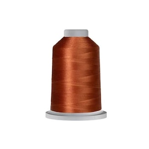 May include: A spool of copper-colored sewing thread featuring a cylindrical shape with a slightly tapered top. The thread is wound tightly around the central core, displaying a smooth, metallic sheen and a consistent, vibrant rust-orange hue.