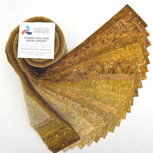May include: A roll of fabric strips in shades of brown and gold, with a floral pattern. The fabric is fanned out, displaying the different patterns and colors. A white card with the text "THANK YOU FOR YOUR ORDER!" is attached to the roll.