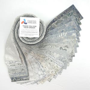 May include: A collection of fabric swatches in shades of gray and blue, fanned out to display various patterns. The fabric is rolled up with a white card that reads "TWISTED THREADS THANK YOU FOR YOUR ORDER!"