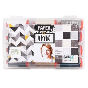 Op de afbeelding: Een transparante kunststof opbergdoos met 12 spoelen Aurifil garen. De spoelen zijn zwart en grijs en hebben een rood label met de tekst "Paper & Ink". De doos heeft ook een label met de tekst "Zen Chic" en een foto van een vrouw. Het label zegt ook "100% Aurifil Cotton, 12 kleuren, 50 wt, 1422yds each".