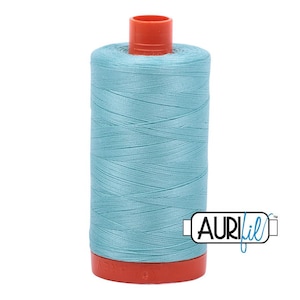 May include: A spool of light blue sewing thread featuring a bright orange plastic top and bottom base. The spool is wrapped in smooth, consistent thread and includes a white rectangular label with the black text AURIfil printed on the side.