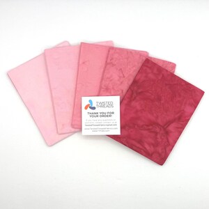May include: Five rectangular fabric swatches arranged in a fan shape, displaying a gradient of pink shades from light pastel to deep magenta. A white square card is placed on top, featuring the text TWISTED THREADS THANK YOU FOR YOUR ORDER.