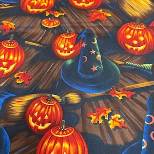 May include: A fabric pattern featuring orange jack-o'-lanterns with glowing yellow faces, dark blue witch hats decorated with pink stars and crescent moons, tan straw brooms, and scattered red and yellow autumn leaves on a dark brown background.