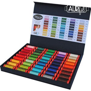 May include: A black presentation box containing 45 small spools of Aurifil cotton thread in a wide spectrum of colors. The lid interior features the Aurifil logo, a Patrick Lose Essentials label, and a printed color chart with corresponding thread numbers.