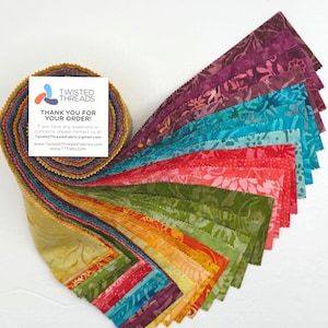 May include: A jelly roll of batik fabric strips in a spectrum of colors including yellow, orange, red, green, blue, and purple, featuring floral and leaf patterns. A square white card with the text TWISTED THREADS THANK YOU FOR YOUR ORDER is attached.