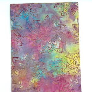 May include: A fabric with a tie-dye effect in shades of pink, purple, blue, and yellow. Large, stylized floral patterns in gold are printed across the surface, creating a vibrant and artistic textile.