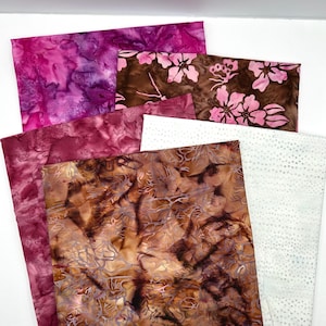 May include: A collection of fabric swatches in various colors and patterns. The fabrics include shades of pink, brown, and white, with designs such as floral prints, abstract swirls, and dotted patterns. The fabrics are arranged in a layered composition.