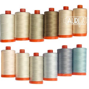 May include: Twelve spools of Aurifil sewing thread arranged in two rows. The spools feature various neutral shades including cream, beige, tan, gray, and light blue, each topped with a bright orange plastic cap and base for consistent identification.