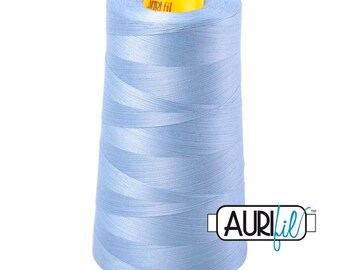 Può includere: Una grande rocca di filo da cucito azzurro avvolto in forma conica. La parte superiore della rocca presenta un tappo in plastica giallo brillante con il testo Auri fil stampato in nero. Il logo Auri fil è visibile anche nell'angolo in basso a destra.
