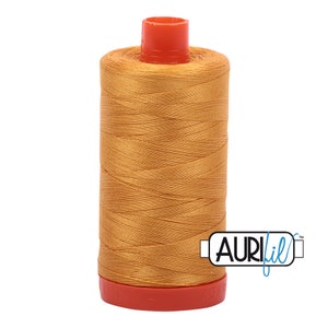 May include: A spool of Aurifil thread in a golden yellow color. The spool is labeled "Aurifil" in blue text.