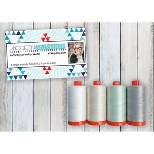 May include: Four large spools of 50wt thread, each containing 1422 yards, presented with a product card labeled MODERN SHIRTINGS by Victoria Findlay Wolfe. The spools are white, off-white, light green, and gray, each featuring a bright orange base.