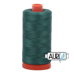 May include: A spool of dark forest green sewing thread with a smooth, tightly wound texture. The spool features a bright orange plastic top and base, with the brand name AuriFil printed in black and blue text on the lower right side.