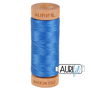 May include: A spool of Aurifil thread in a bright blue color. The spool is made of wood and has the Aurifil logo printed on it. The text "Made in Italy" is printed on the bottom of the spool.