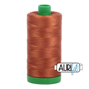 May include: A spool of brown Aurifil thread with a green plastic bobbin.