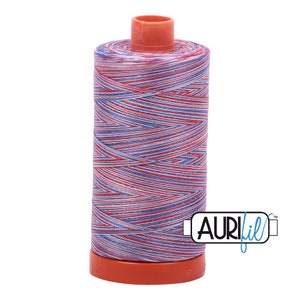 May include: A spool of Aurifil thread, featuring a vibrant mix of red, white, and blue threads. The thread is tightly wound around a cylindrical core with a matching orange base and top. The Aurifil logo is visible.