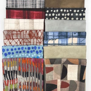 May include: A collection of ten folded fabric swatches arranged in two columns. Patterns include black and white grid, red plaid, beige check, brown geometric lines, blue dots, multicolored vertical stripes, solid brown, white dots, gray, blue plaid, solid tan, and abstract shapes.