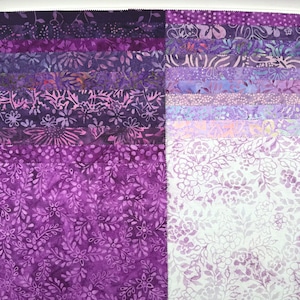 May include: A collection of fabric squares arranged in a grid, featuring a gradient of purple shades ranging from deep violet to light lavender and white. Each square displays intricate batik-style floral, leaf, and dotted patterns throughout.