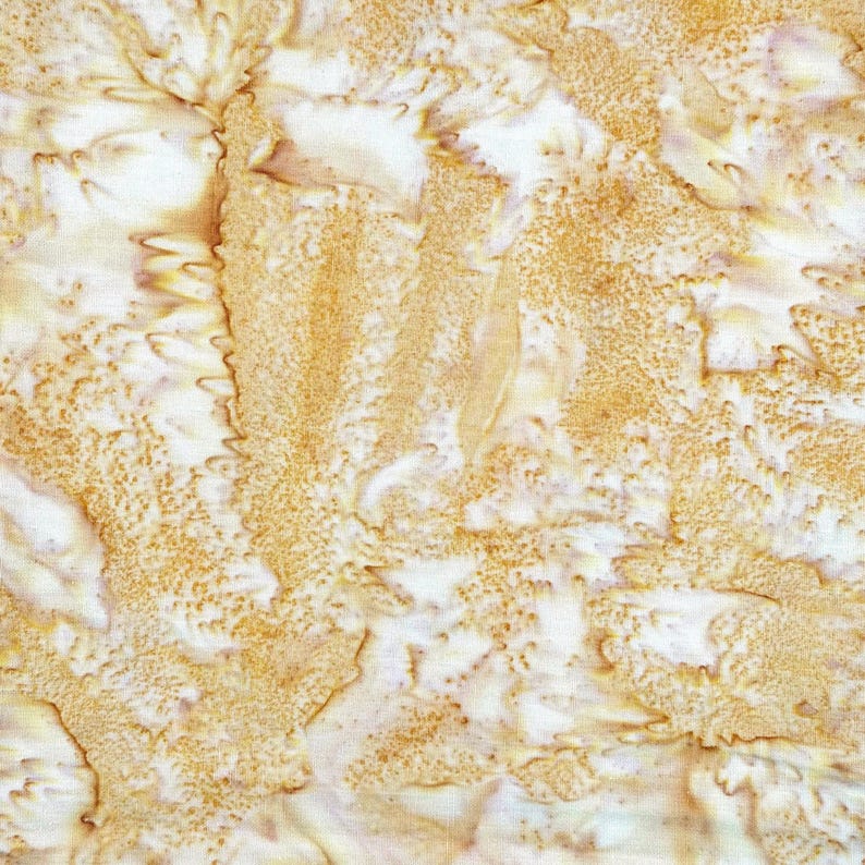 Puede incluir: Una pieza de tela con un patr&oacute;n batik sobre una base blanca, con formas org&aacute;nicas texturizadas y moteadas en amarillo dorado y marr&oacute;n claro. El dise&ntilde;o muestra un efecto craquelado de reserva de cera con intensidad de color variable.