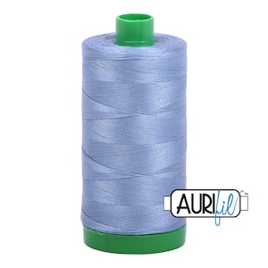 May include: A spool of light blue thread with a green plastic top and bottom. The spool is labeled "Aurifil" in blue lettering.