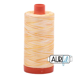 May include: A spool of sewing thread featuring a variegated pattern of white and orange fibers wound around a cylindrical core. The spool has a solid orange plastic top and base, with the brand name AuriFil printed in black on a white label.
