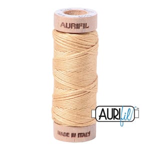 May include: A spool of light beige sewing thread wrapped around a wooden core. The top of the wooden spool is printed with the brand name AURIFIL and the number 5001. The bottom of the spool is printed with the text MADE IN ITALY.