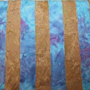May include: A fabric featuring a repeating vertical striped pattern. The stripes alternate between a solid, textured tan color and a mottled, marbled blend of bright blue and purple hues. The textile displays a consistent, repeating design throughout.