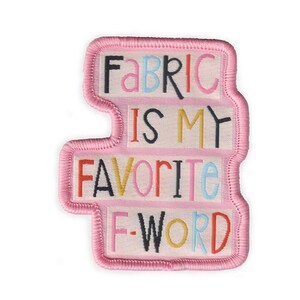 May include: A pink embroidered patch with the words "FABRIC IS MY FAVORITE F-WORD" in colorful letters. The patch has a light pink border and a white background for the text. The patch is a fun and quirky accessory.