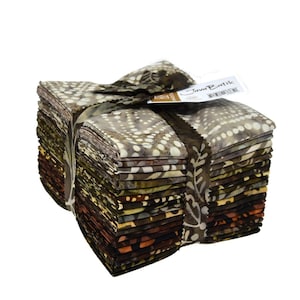 May include: A stack of folded fabric squares featuring Java Batik patterns in shades of brown, tan, and cream. The fabric bundle is secured with a matching fabric strip and includes a white tag with the text Java Batik printed on the top.