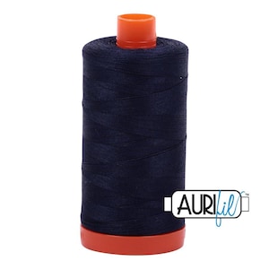 May include: A cylindrical spool of dark navy blue sewing thread featuring a bright orange plastic top and base. The spool is wrapped in smooth thread and includes a white rectangular logo with the black text Auri and blue script fil.