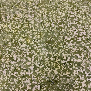 May include: Green fabric with a white floral pattern. The fabric has a batik style design with a repeating pattern of small leaves and branches.