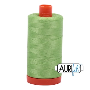 May include: A spool of green thread with a red top and bottom. The thread is labeled "Aurifil" in blue.