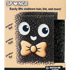 May include: A black Spunge lint remover in a cardboard box. The Spunge has large white eyes, a small smile, and a tan bow tie. Text on the box reads "Easily lifts stubborn hair, lint, and more!" and "Hey, I'm Spunge. Nice to meet you!"